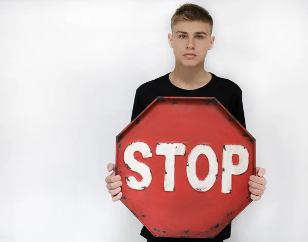 Un adolescente con un símbolo de parada, parada, sobre un fondo blanco en un — Foto de Stock