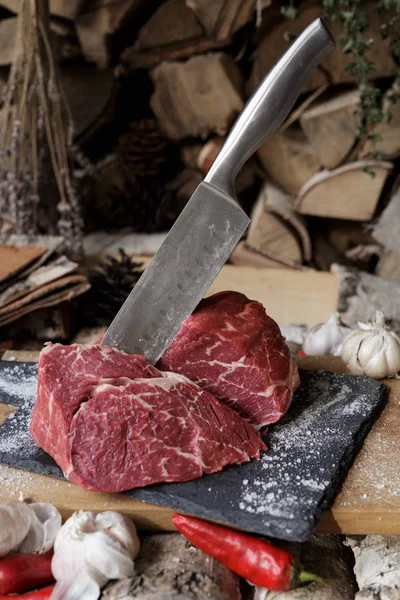 Świeże mięso z nożem na cięcia czarny deska, nadal życia w — Zdjęcie stockowe