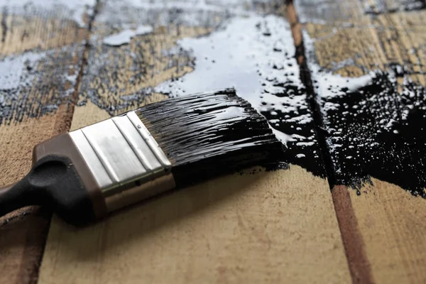 Щетка с черной краской на поверхности дерева. Покраска дерева — стоковое фото