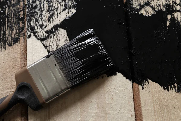 brush with black paint on the wood surface. painting the wood wi