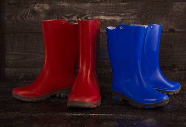 ahşap arka plan üzerinde kırmızı mavi çocuk lastik çizmeler. 