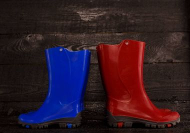 ahşap arka plan üzerinde kırmızı mavi çocuk lastik çizmeler. 