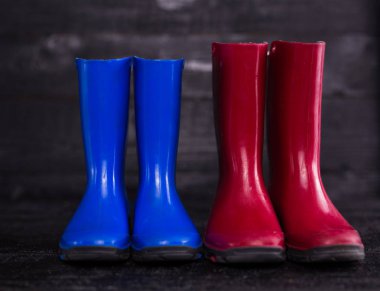 ahşap arka plan üzerinde kırmızı mavi çocuk lastik çizmeler. 