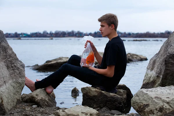 goldfish in a bag in the hands of a teenager on the beach.