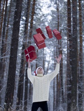 Genç şapkalı Noel Baba hediye kar karlı bir ormandaki toplar,