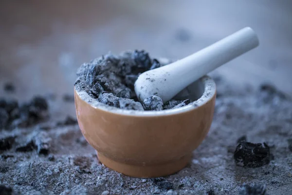 The pestle for spices filled with ashes. the burned coal in a po — Stock Photo, Image