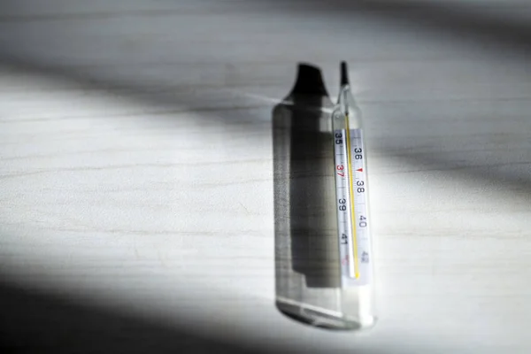 Medical thermometer in bright shadows from the window light on a — 스톡 사진