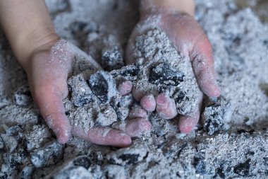 Bir çocuğun elinde yanmış küller. Yaklaş.