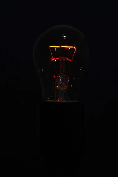 Žárovka na černém pozadí s hořící spirálou — Stock fotografie