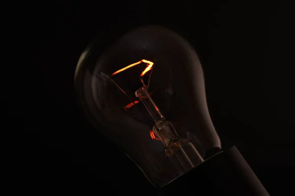 Glödlampa på en svart bakgrund med en brinnande spiral — Stockfoto