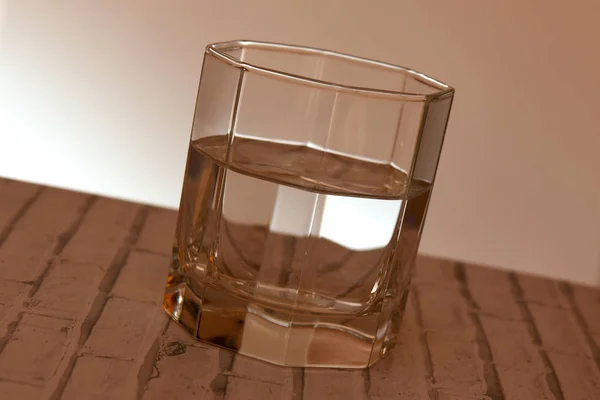 Faceted glass with clear water or liquid — Stock Photo, Image