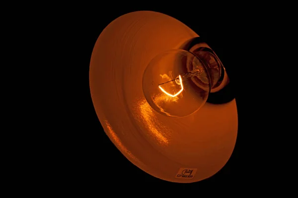 Light bulb on a black background with a burning spiral — Stock Photo, Image