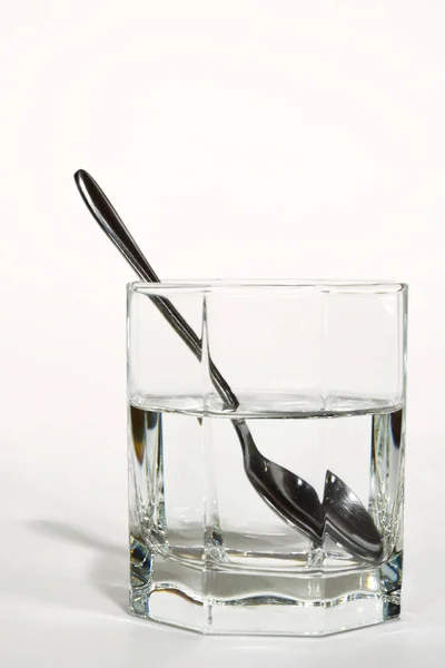 澄んだ水の入ったガラスの中のスチールスプーン — ストック写真