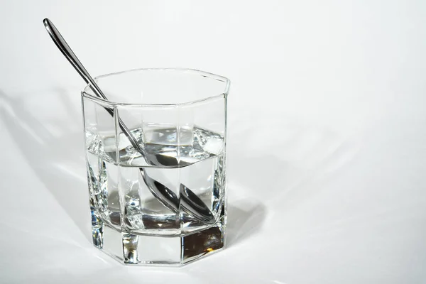 澄んだ水の入ったガラスの中のスチールスプーン — ストック写真