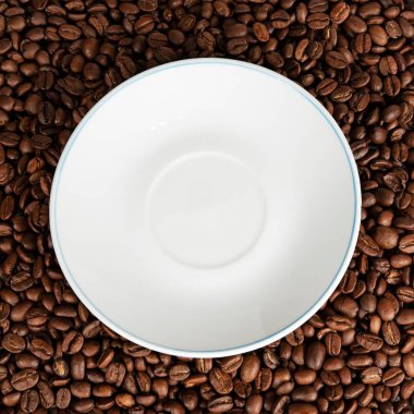 Kahve çekirdekleri üzerinde beyaz çay tabağı