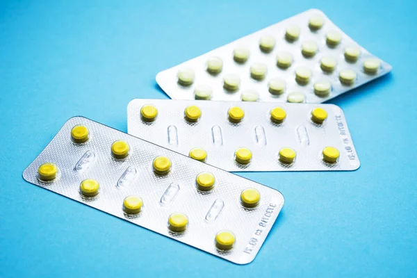 Pilulky v blistrech balení na modrém pozadí — Stock fotografie