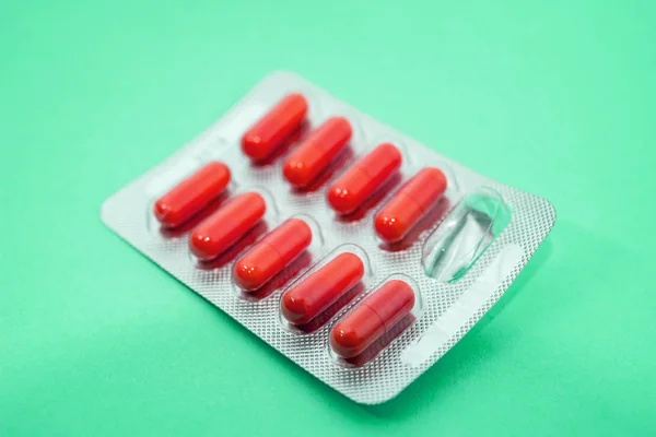 Red pills in blister packs on green background — Stok fotoğraf