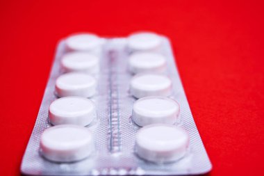Kırmızı arkaplanda beyaz hap paketi, yatay yakın plan