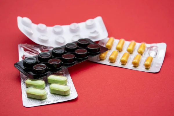 药包里的药丸堆在一起 红色背景 — 图库照片