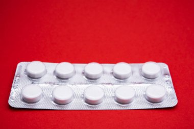 Kırmızı arkaplanda beyaz hap paketi, yatay yakın plan