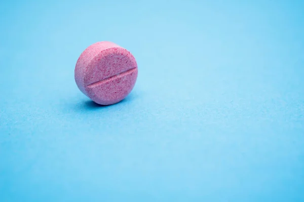 Eine Runde Rosa Pille Auf Der Rippe Nahaufnahme Blauer Hintergrund — Stockfoto