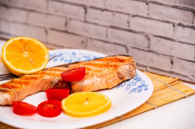 Domatesli kızarmış somon ve tabakta limon, yatay fotoğraf.