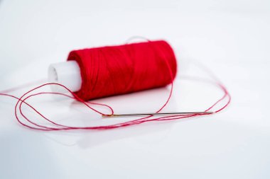 İplik makarasının arka planında kırmızı iplik olan iğne, yatay fotoğraf