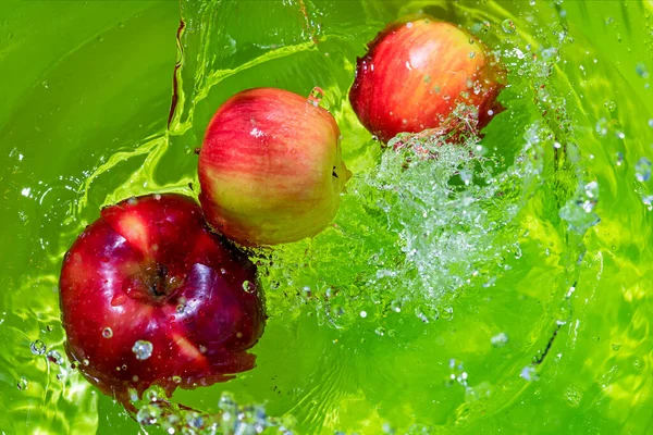 Tres Manzanas Sobre Fondo Verde Las Olas Con Salpicaduras Agua — Foto de Stock