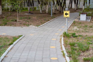 Parktaki bir patikada sarı ok işaretçisi, yaz çekimi, yatay