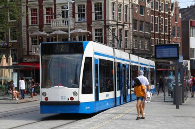 AMSTERDAM, NETHERLANDS - 8 Temmuz 2017: İnsanlar Hollanda, Amsterdam 'da GVB elektrikli tramvayına (Siemens yapımı Combino modeli) biniyor. GVB yılda 211 milyon turla hizmet veriyor.