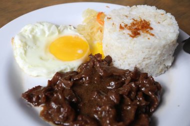 Tapsilog kahvaltısı - Filipinler 'de tipik sabah yemeği. Sarımsaklı pilav, sahanda yumurta ve ızgara sığır eti..