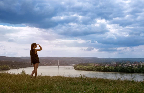 Žena se dívá přes řeku na cit — Stock fotografie