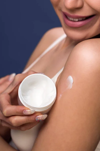 Женщина держит банку крема и наносить крем на кожу близко у — стоковое фото