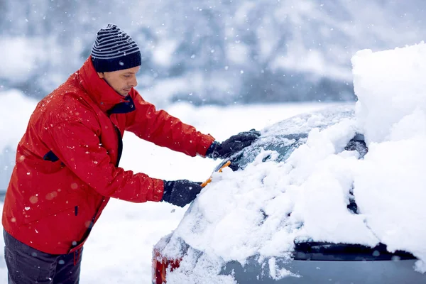 Clima nevado de invierno. Coche en nieve después de la tormenta de nieve. hombre quitando nieve del coche . —  Fotos de Stock