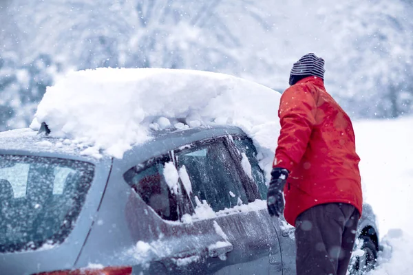 Samochód utknął w śniegu. Człowiek zmywający śnieg z samochodu w zimowy dzień — Zdjęcie stockowe