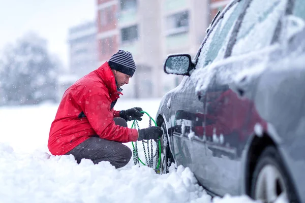 Ο άνθρωπος που βάζει τις χειμερινές αλυσίδες στο αυτοκίνητο. Μπερδεμένος άνθρωπος δεν ξέρει πώς Royalty Free Εικόνες Αρχείου