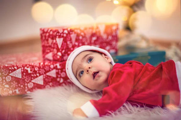 Niedliches Baby mit Weihnachtsmütze auf dem Boden zu Hause. Weihnachtsfeier — Stockfoto