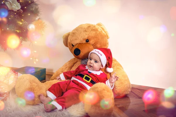 Noel Baba kostümlü çocuk ve oyuncak ayı. Noel Baba kıyafetleri giyen mutlu çocuk.. — Stok fotoğraf