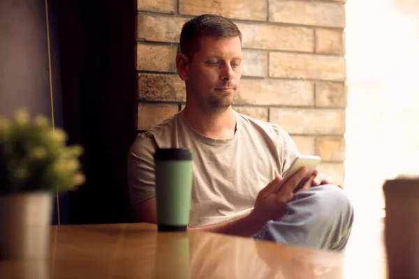 Hombre usando el teléfono inteligente en cafe.Man relajarse en la cafetería y beber café . — Foto de Stock