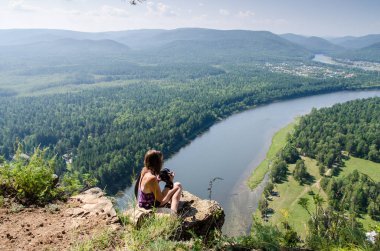 Nehrin üzerinde bir kayaya oturan genç kadın