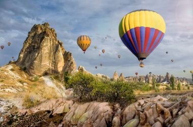 Kapadokya Türkiye 'de kayaların üzerinde uçan sıcak hava balonu