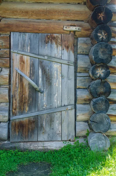 Фрагмент старой потрескавшейся бревенчатой стены и деревянной двери — стоковое фото