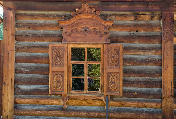 Das Fenster mit dem geschnitzten Holzarchitrav im alten Holzhaus in der alten russischen Stadt. — Stockfoto