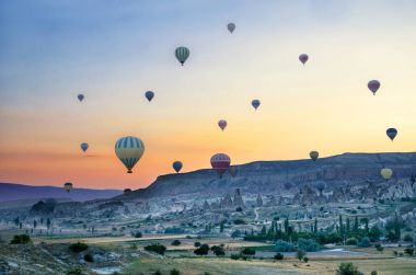 Kapadokya Türkiye 'de kayaların üzerinde uçan sıcak hava balonu