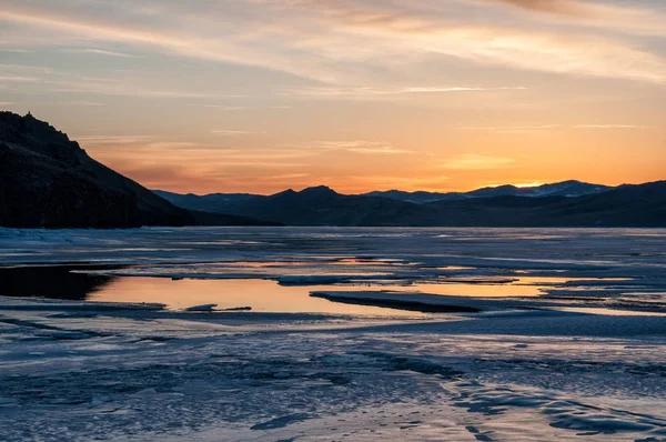 Hielo y agua cerca de la montaña en el lago congelado Baikal antes del amanecer —  Fotos de Stock