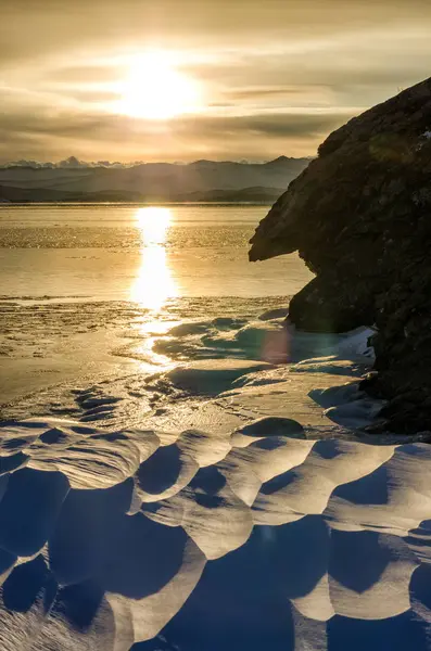 Zonsondergang in de winter in de buurt van de rotsen met sneeuw de bevroren Baikal Lake — Stockfoto