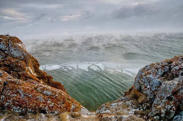 Lago Baikal y roca en el frío de diciembre. Tiempo de congelación. Los témpanos de hielo nadan en el agua — Foto de Stock
