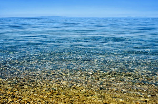 Παραλία με βότσαλο και γαλαζοπράσινα νερά κάτω από το γαλάζιο του ουρανού — Φωτογραφία Αρχείου