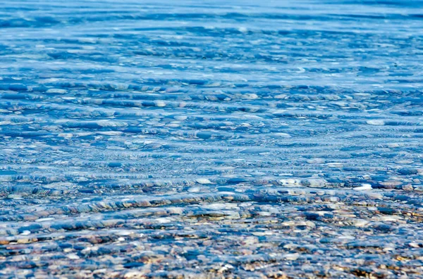Strand mit Kiesel und türkisfarbenem Wasser unter blauem Himmel — Stockfoto