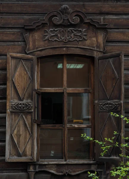 La ventana con el arquitrabe tallado en madera en la antigua casa de madera en el casco antiguo ruso . — Foto de Stock